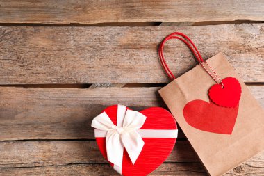 Kağıt torba ve kalp şeklinde hediye kutusu tahta arka planda, düz yerde. Metin için boşluk