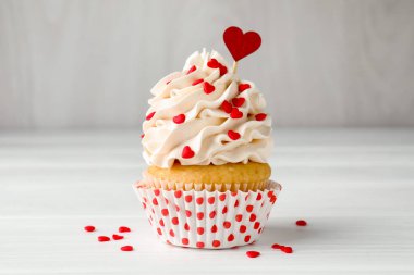 Sevgililer Günün kutlu olsun. Gri duvarın yakınındaki beyaz ahşap masada kalp şeklinde serpiştirilmiş lezzetli kek.