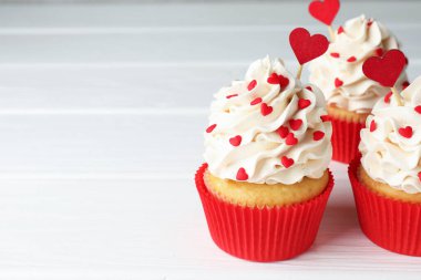 Sevgililer Günün kutlu olsun. Beyaz ahşap masadaki kalplerin şekline bürünmüş, serpiştirilmiş lezzetli kekler, yakın plan. Metin için boşluk