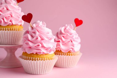 Sevgililer Günün kutlu olsun. Pembe arka planda kırmızı kalp kaplamalı lezzetli kekler, yakın plan. Metin için boşluk