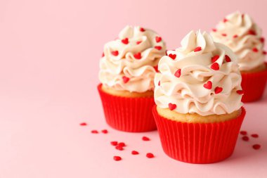 Sevgililer Günün kutlu olsun. Pembe arka planda kırmızı kalpleri olan lezzetli kekler, yakın plan. Metin için boşluk