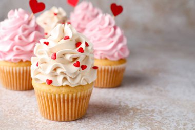 Sevgililer Günün kutlu olsun. Gri masada kırmızı kalpleri olan lezzetli kekler, yakın plan. Metin için boşluk