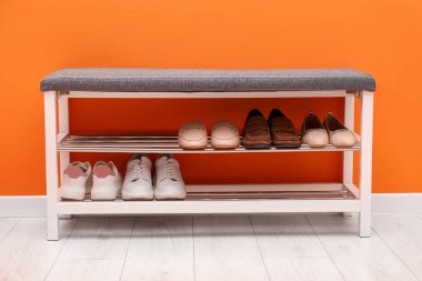 Kapalı alanda turuncu duvarın yanında farklı ayakkabılar olan ayakkabı deposu.