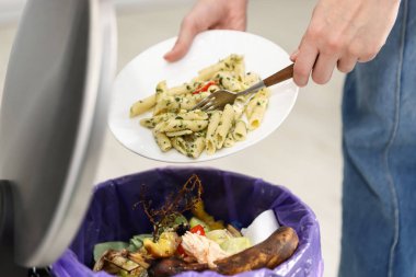 Mutfaktaki çöp tenekesine yemek atan kadın, yakın plan.