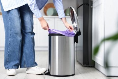 Mutfaktaki çöp kutusuna çöp torbası koyan kadın, yakın plan.