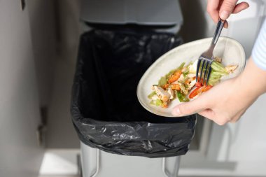 Mutfaktaki çöp tenekesine yemek atan kadın, yakın plan.