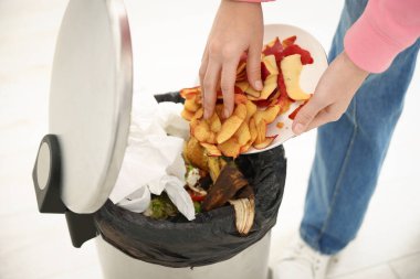 Kadın mutfaktaki çöp kutusuna elma kabuğu atıyor, yakın plan.