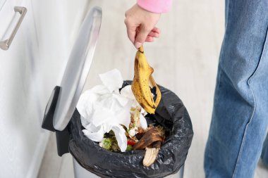 Mutfaktaki çöp kutusuna muz kabuğu atan kadın, yakın plan.