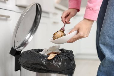 Mutfaktaki çöp tenekesine yemek atan kadın, yakın plan.