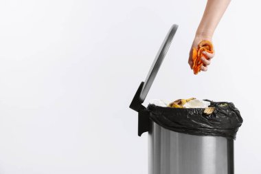 Mandalina kabuklarını beyaz arka planda çöp kutusuna atan kadın, yakın plan. Metin için boşluk