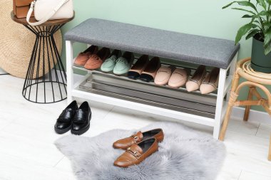 Farklı ayakkabı, aksesuar ve yeşil duvarın yanındaki ev bitkilerinden oluşan ayakkabı deposu.