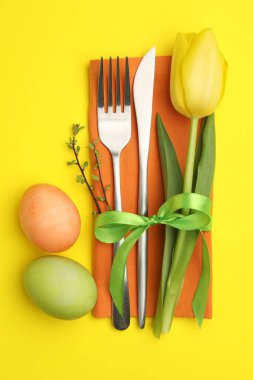 Paskalya kutlaması. Çiçek desenli şenlik masası ve sarı arka planda boyanmış yumurtalar.