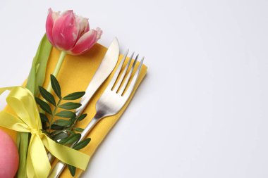 Paskalya sofrası. Beyaz arka planda lale ve boyalı yumurta ile güzel gümüş takımlar, yakın plan. Metin için boşluk