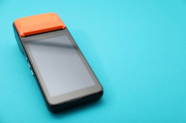 Açık mavi arka planda bir ödeme terminali, yakın plan. Metin için boşluk