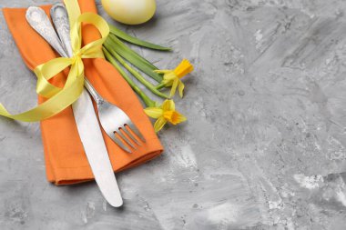 Paskalya sofrası. Gri desenli arka planda nergisleri olan güzel gümüş takımlar, yakın plan. Metin için boşluk