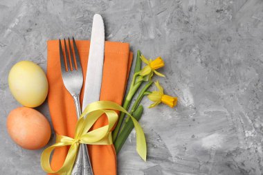 Paskalya sofrası. Gri desenli arka planda nergisleri olan güzel gümüş takımlar, üst manzara. Metin için boşluk