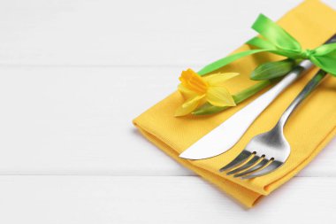 Paskalya sofrası. Beyaz ahşap arka planda nergis çiçeği olan güzel gümüş takımlar, yakın plan. Metin için boşluk