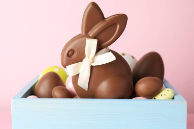 Çikolatalı Paskalya tavşanı ve pembe arka planda yumurtalar, yakın plan.