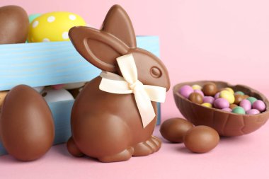 Çikolatalı Paskalya tavşanı ve pembe arka planda yumurtalar, yakın plan.