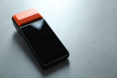 Açık gri masada bir ödeme terminali, yakın plan. Metin için boşluk