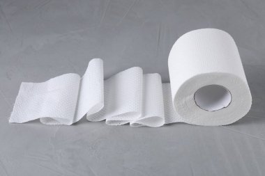 Gri masadaki tuvalet kağıdı rulosu, yakın plan.