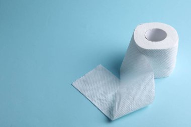 Açık mavi arka planda tuvalet kağıdı rulosu, yakın plan. Metin için boşluk