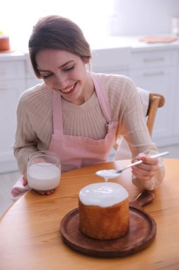Genç bir kadın geleneksel paskalya pastasını mutfakta jöleli dekore ediyor.