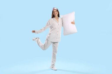 Maske takan güzel bir kadın ve açık mavi arka planda yastıklı şık pijamalar.