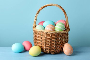 Masadaki sepetteki güzel Paskalya yumurtaları açık mavi arka planda