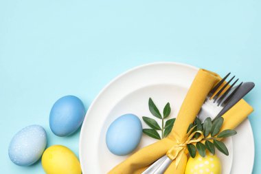 Paskalya kutlaması. Yeşil yapraklı şenlik masası ve açık mavi arka planda boyanmış yumurtalar. Metin için boşluk