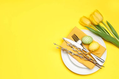 Paskalya kutlaması. Lale çiçekleri, boyalı yumurtalar ve sarı arka planda söğüt dalları olan şenlik masası düzlüğü. Metin için boşluk