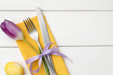 Paskalya sofrası. Lale ve beyaz ahşap arka planda boyalı yumurta ile güzel gümüş takımlar, üst manzara. Metin için boşluk