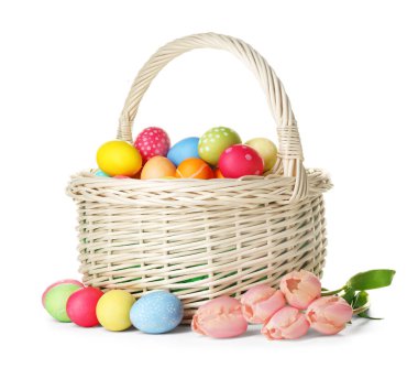 Hasır sepete boyanmış Paskalya yumurtaları ve beyaza izole edilmiş güzel laleler.