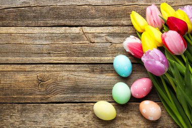 Boyanmış Paskalya yumurtaları ve ahşap masa üzerinde güzel laleler, düz bir döşeme. Metin için boşluk
