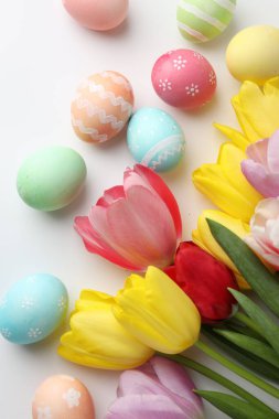 Boyalı Paskalya yumurtaları ve beyaz arka planda güzel laleler.