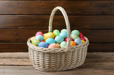 Hasır sepete boyanmış Paskalya yumurtaları ve ahşap masada güzel laleler.