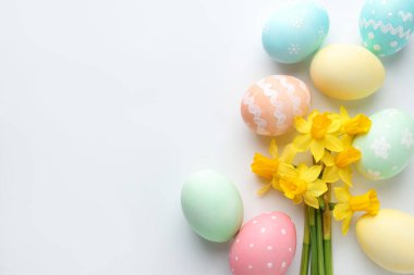 Paskalya yumurtaları ve beyaz arka planda güzel nergisler. Metin için boşluk