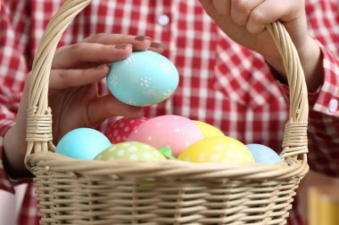 Paskalya sepetinde yumurta boyalı bir kadın, kapalı bir masada, yakın plan.