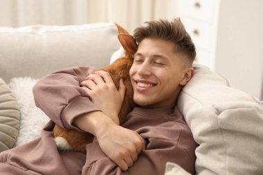 Evdeki kanepede sevimli tavşanı olan mutlu adam.