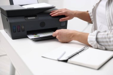 Beyaz masadaki yazıcıdan baskı kağıdı alan adam, yakın plan.