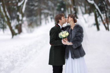 Bir buket çiçekli mutlu yeni evli çift kış günü dışarıda öpüşüyor, mesaj atmak için yer var.