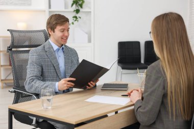 Dosyasıyla gülümseyen eleman ve adayın ofiste iş görüşmesi var.