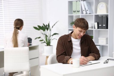 Meslektaşı ofisteki beyaz masada yazarken, kadın yazıcı kullanıyor, seçici odaklanma