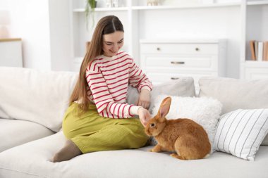 Evdeki kanepede sevimli tavşanlı mutlu kadın. Metin için boşluk