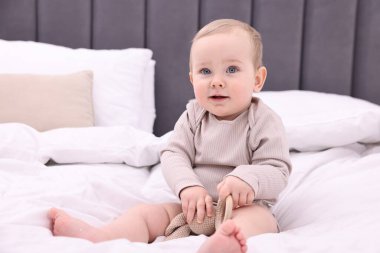 Evde yatakta oturan oyuncak ile sevimli küçük bebek