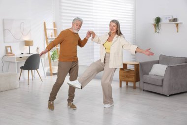 Mutlu yaşlı çift evde dans ediyor.
