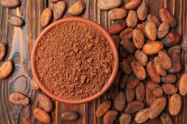 Doğal kakao çekirdeği ve toz tahta masada, düz yerde.