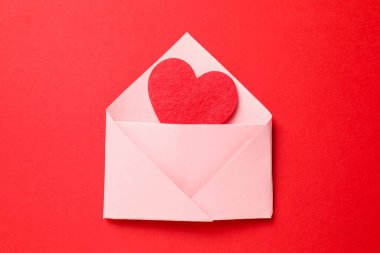 Sevgi. Kırmızı arkaplanda dekoratif kalpli zarf, üst görünüm