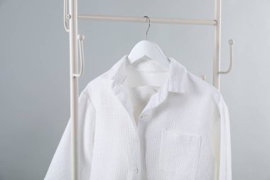 Açık gri arkaplanda asılı şık pijama gömleği, yakın plan