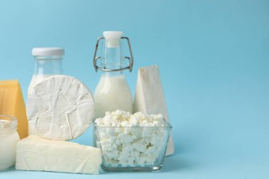 Açık mavi arka planda farklı süt ürünleri, yakın plan. Metin için boşluk